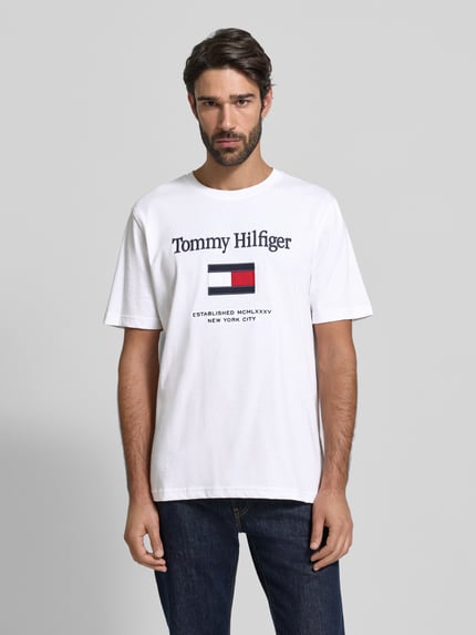 Männermodel trägt Regular Fit T-Shirt aus reiner Baumwolle von Tommy Hilfiger in Weiß mit Label-Schriftzug, Rundhals, Jersey, Ganzkörperansicht von vorne