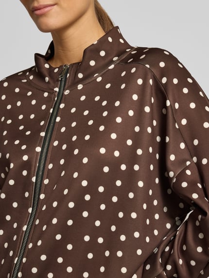 Frauenmodel trägt Jacke im Allover-Look Modell 'Is44ina' von ZABAIONE, braun mit weißen Punkten, Reißverschluss, Nahaufnahme Oberkörper. Material-Mix mit Stretch-Anteil, Regular Fit, Stehkragen.