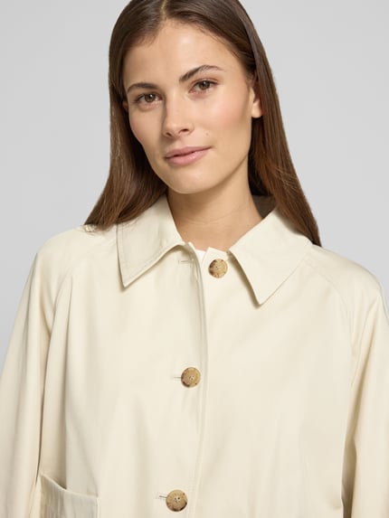 Frauenmodel trägt Relaxed Fit Trenchcoat aus reiner Baumwolle von Tommy Hilfiger in Unifarben, Twill-Struktur, Nahaufnahme Oberkörper.