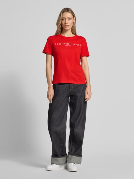 Frauenmodel trägt Regular Fit T-Shirt aus reiner Baumwolle von Tommy Hilfiger in Optik: Unifarben, Logo-Detail, Label-Schriftzug, Rundhals, Kurzarm, Materialverarbeitung: Jersey, Ganzkörperansicht von vorne.