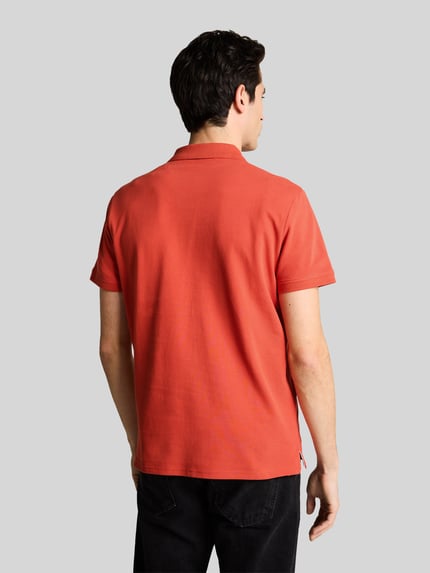 Męski model nosi Regular Fit Poloshirt aus reiner Baumwolle od Tom Tailor, pomarańczowy, jednolity, bawełna piké, tył, krój regular fit, widok całej sylwetki z tyłu.