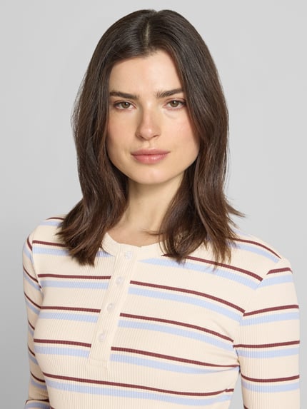 Vrouwenmodel draagt Slim Fit Langarmshirt uit katoenmix model 'KATIE' van Vero Moda, meerkleurige gestreepte look, fijngebreid. Nahaufnahme bovenlichaam.