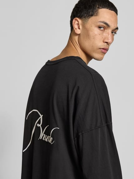 Männermodel trägt Regular Fit Longsleeve aus katoen van RHUDE, zwart met labelstitchings, ronde hals, ruglengte maat M 62 cm, Ganzkörperansicht Rückansicht