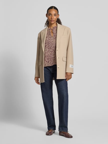Frauenmodel trägt Regular Fit Langarmbluse mit Bindeverschluss Modell 'DITSY' von ONLY, Damen Langarmbluse, gemustert in Rot-Beige, kombiniert mit beigem Blazer, Gerade geschnittene Jeans und braunen Schuhen, Ganzkörperansicht von vorne.