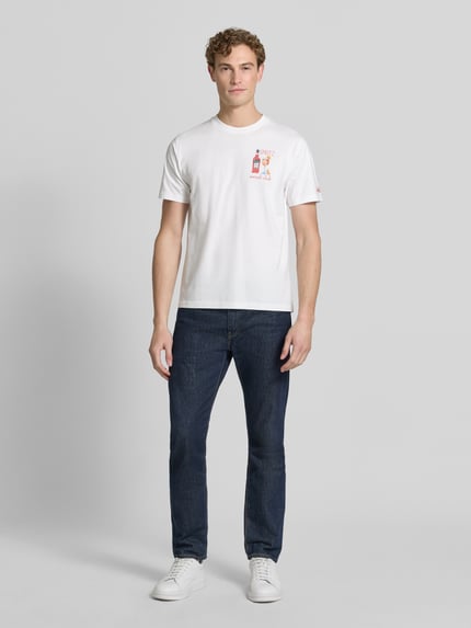Männermodel trägt Herren T-Shirt mit Stitchings Modell 'PORTOFINO' von MC2 Saint Barth, Reine Baumwolle, Regular-Fit, Rundhalsausschnitt, Rückenlänge bei Größe M 68 cm, Weiß mit dezentem Aufdruck, Ganzkörperansicht von vorne.