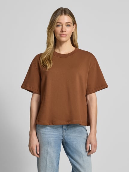 Vrouwenmodel draagt Sweatshirt mit 1/2-Arm und Rundhalsausschnitt van Rich & Royal in bruin, bio-katoenmix met stretch, loose fit, ronde hals, verlaagde schouders, korte mouw en zijsplitten, voorkant volledige lichaamsperspectief.