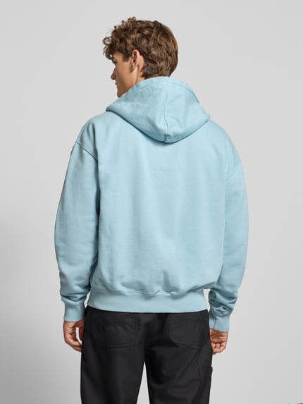 Männermodel trägt Oversized Sweatjacke mit Logo von Pegador aus Baumwoll-Mix, Kapuze, Känguru-Tasche, Rückansicht, Ganzkörperansicht.