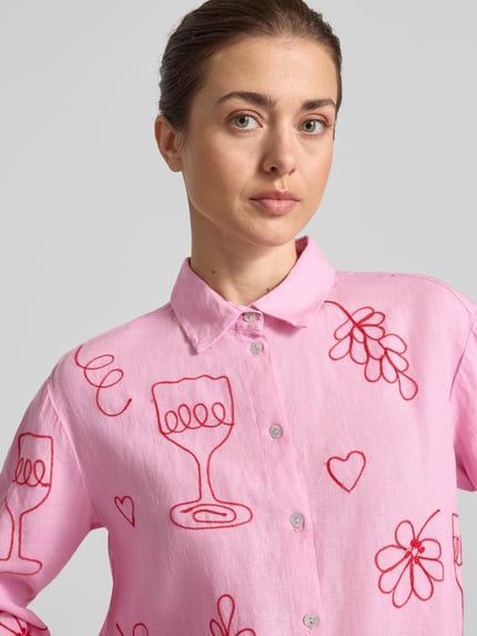 Frauenmodel trägt Regular Fit Leinenbluse im Allover-Look von Christian Berg Woman in Rosa mit roten Stickmustern, reine Leinen, Hemdblusenkragen, Knopfleiste, Nahaufnahme Oberkörper.