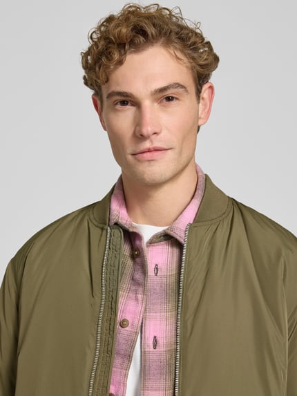 Männermodel trägt olivgrüne Regular Fit Bomberjacke mit Baseball-Kragen Modell 'CHARLES' von Selected, Herren Bomberjacke, Nahaufnahme Oberkörper.