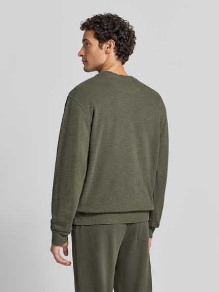 Męskimodel nosi Regular Fit Sweatshirt aus Baumwoll-Mix von Scotch & Soda, mieszanka bawełny, okrągły dekolt, elastyczne wykończenia, długość tyłu w rozmiarze M: 61 cm, długość rękawów w rozmiarze M: 70 cm, widok całej sylwetki z tyłu.