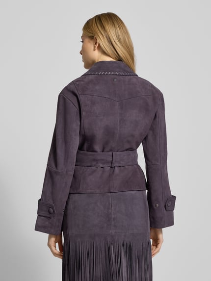 Frauenmodel trägt Lederjacke mit Bindegürtel von Marc Cain in dunklem Violett, Echtleder, taillierter Schnitt, Reverskragen, Ganzkörperansicht Rückansicht.