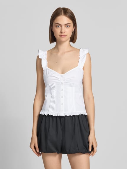 Frauenmodel trägt Slim Fit Bluse mit Rüschenbesatz von Gina Tricot, weiße Farbe, Knopfleiste, Spaghetti-Träger, Ganzkörperansicht von vorne.