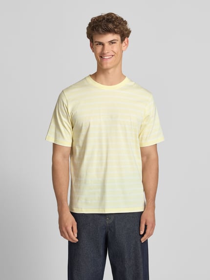 Männermodel trägt T-Shirt mit Streifenmuster und Label-Stitching von Jack & Jones in Gelb, Reine Baumwolle, Relaxed-Fit, Rundhalsausschnitt, Rückenlänge bei Größe M 72 cm, Ganzkörperansicht von vorne.