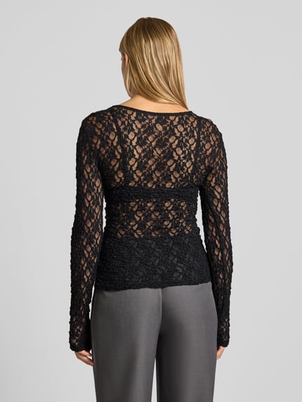 Vrouwenmodel draagt zwart shirt met lange mouwen met ronde hals, transparant kant, Dames Slim Fit Langarmshirt met Rundhalsausschnitt model 'HAZEL' van PIECES, volledige achteraanzicht