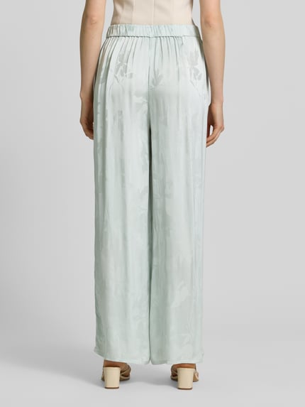 Frauenmodel trägt Weite Hose aus reiner Viskose von Calvin Klein Womenswear, Optik:Allover-Muster, Passform: Wide-Leg, Bundabschluss: elastisch, seitliche Eingrifftaschen, Materialverarbeitung: Jacquard, Material: reine Viskose, hellgrüne Farbtöne, fließende Oberfläche, Ganzkörperansicht Rückansicht.