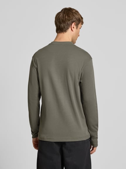 Männermodel trägt Langarmshirt mit kleinem Logo-Schriftzug von G-Star RAW in Oliv, strukturierte Jersey-Optik, Ganzkörperansicht Rückansicht.