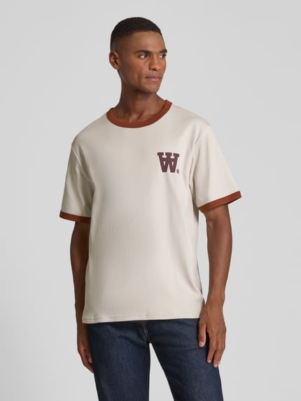 Männermodel trägt T-Shirt mit geripptem Rundhalsausschnitt Modell 'Parker' von Wood Wood aus reiner Baumwolle, lockerer Schnitt, Label-Print, Ganzkörperansicht von vorne.