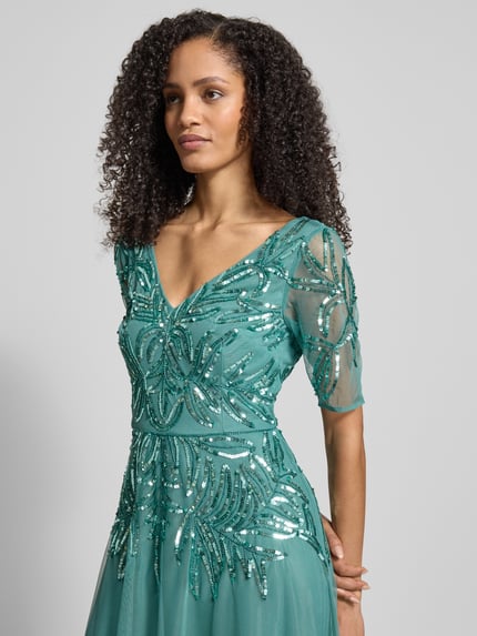 Vrouwenmodel draagt Avondjurk met bloemmotief van pailletten van Adrianna Papell, getailleerde pasvorm, V-hals, mesh, korte mouw, onderrok, naadritssluiting, kleur groen, detailopname bovenlichaam.