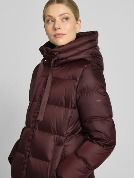 Frauenmodel trägt Regular Fit Daunenmantel mit Label-Print von Marc O'Polo in dunklem Bordeauxrot mit glatter, gesteppter Struktur, Nahaufnahme Oberkörper. Damen Daunenmantel von Marc O'Polo.