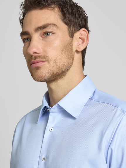 Männermodel trägt Regular Fit Business-Hemd mit Kentkragen von ETERNA aus Reine Baumwolle, hellblau, durchgehende Knopfleiste, Nahaufnahme Oberkörper.