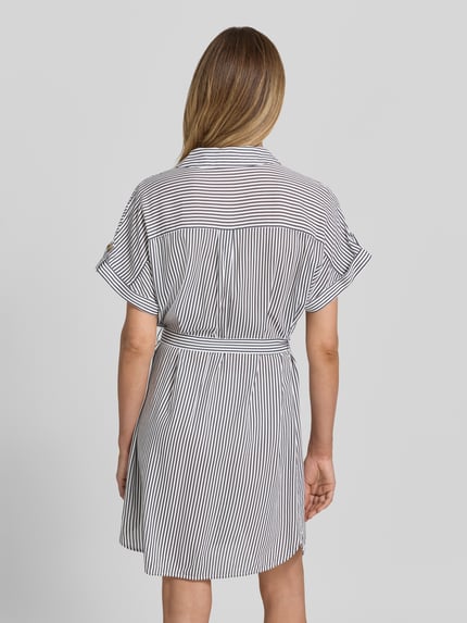 Vrouwenmodel draagt vrijetijdsjurk van Vero Moda, model 'BUMPY', look: effen, minilengte, V-hals, zuiver viscose, achterpas, popeline, knoopsluiting, korte mouw, rugaanzicht, geheel in beeld.