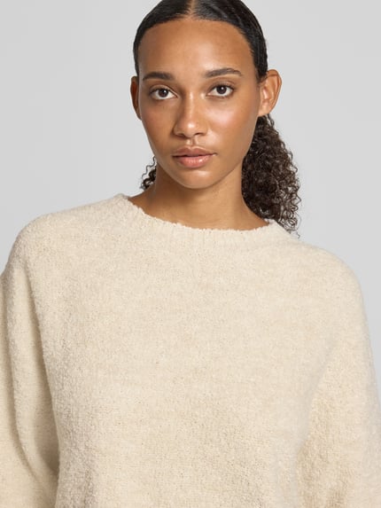 Frauenmodel trägt Relaxed Fit Pullover mit Lanawoll-Anteil von Rich & Royal, cremefarben, Strick-Optik, Rundhalsausschnitt, Nahaufnahme Oberkörper.