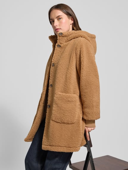 Kobiece modelka nosi Regular Fit Teddy-Mantel mit Kapuze od Tom Tailor Denim w jednolitym beżowym kolorze, tekstura tkaniny teddy, widok z przodu w półzbliżeniu.