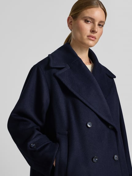 Frauenmodel trägt Regular Fit Mantel aus Woll-Mix Modell 'C_Cisabena' von BOSS Orange in Dunkelblau, glatte Textur, Nahaufnahme Oberkörper.