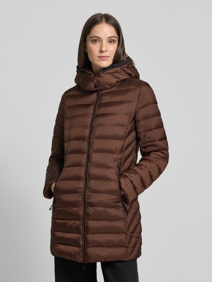 Frauenmodel trägt Steppjacke mit Zweiwege-Reißverschluss von FUCHS SCHMITT in Braun, gesteppt, glatte Oberfläche, Ganzkörperansicht von vorne. Slim Fit, Kapuze, Reißverschlusstaschen, Rückenlänge 83 cm, Schulterbreite 42 cm, Brustweite 51 cm, Ärmellänge 64 cm.