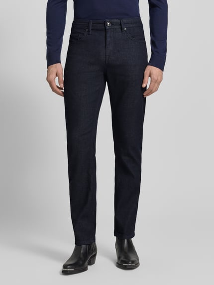 Männermodel trägt Straight Fit Jeans mit 5-Pocket-Design Modell 'Fortress' von JOOP! Collection in dunklem Blau, Baumwoll-Mix mit Stretch-Anteil, Gerader Schnitt, Knopf- und Reißverschluss, Ganzkörperansicht von vorne.