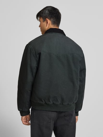 Männermodel trägt Jacke mit Reißverschluss und Label-Detail Modell 'Santa Fe' von Carhartt Work In Progress in Dunkelgrün, Baumwolle, Ganzkörperansicht Rückansicht. Regular Fit, Umlegekragen, sichtbare Textur und Nähte, KI-modifiziertes Bild.