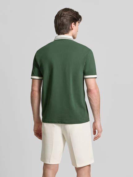 Männermodel trägt Regular Fit Poloshirt mit Logo-Print von EA7 Emporio Armani in Dunkelgrün und Weiß, Rückenansicht Ganzkörperansicht