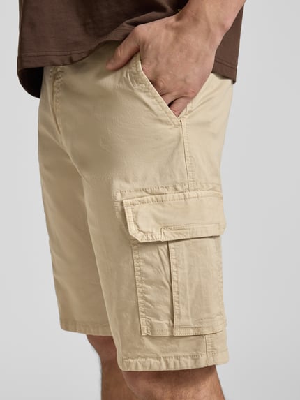 Männermodel trägt Bermudas mit Cargotaschen von bugatti in Beige, Regular Fit, sichtbare Cargotaschen, Nahaufnahme Oberschenkel seitlich.