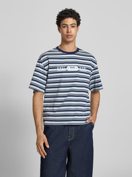 Männermodel trägt Regular Fit T-Shirt mit Logo-Stitching von KARL KANI, Streifenmuster, Reine Baumwolle, Rundhalsausschnitt, Ganzkörperansicht von vorne.