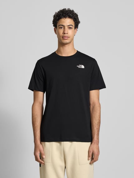 Männermodel trägt Regular Fit T-Shirt aus Baumwoll-Mix Modell 'EVOLUTION' von The North Face, Schwarz, Label-Detail, Ganzkörperansicht von vorne. Herren T-Shirt, Rundhalsausschnitt, Rückenlänge bei Größe M 70 cm.