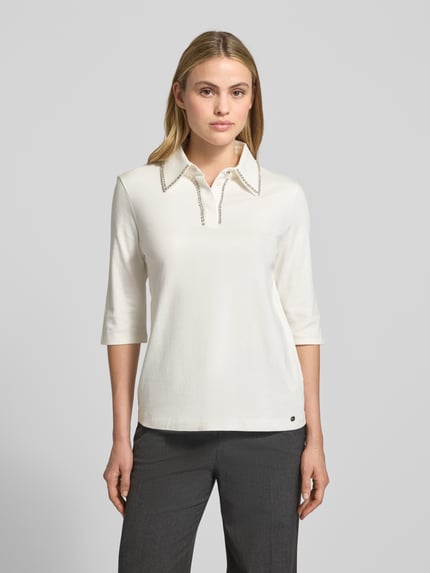Modelka kobieca nosi Blusenshirt mit Umlegekragen und Ziersteinbesatz od Marc Cain, biała bawełna, regular fit, 3/4 rękaw, widok z przodu.