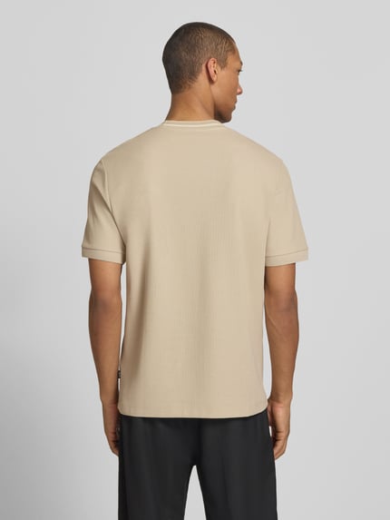 Männermodel trägt Regular Fit T-Shirt aus reiner Baumwolle Modell 'C-TAUT-40' von BOSS in Beige, unifarben, Rückansicht, Piqué-Textur.