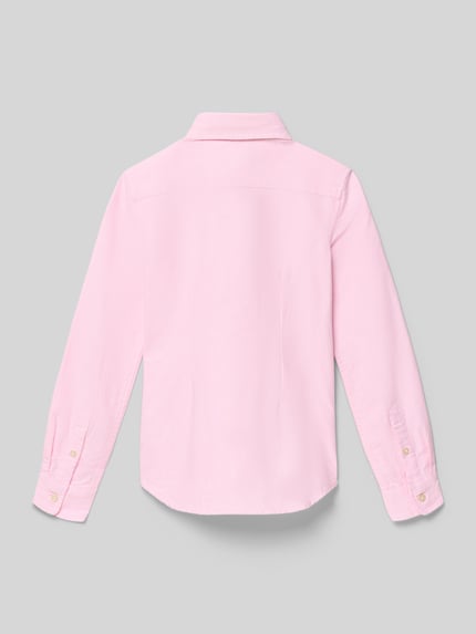 Mädchen trägt Regular Fit Hemdbluse aus reiner Baumwolle Modell 'TRINETTEOX-SHIRTS-BUTTON' von Polo Ralph Lauren Teens, jednolity różowy kolor, długi rękaw, krój regular fit, pikowana struktura, zapięcie na guziki, naszywane logo, bawełna, Ganzkörperansicht Rückansicht.