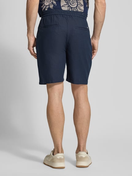 Mannelijk model draagt donkerblauwe korte broek van Scotch & Soda, Model 'FAVE', mix van katoen en linnen, regular fit, elastische band, bandwijdte maat 32: 42 cm, binnenbeenlengte maat 32: 21 cm, volledig aanzicht achterkant.