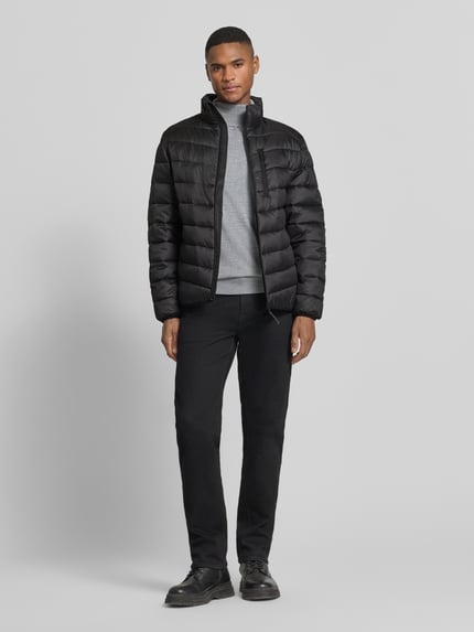 Männermodel trägt Regular Fit Steppjacke mit vertikaler Reißverschlussbrusttasche von Tom Tailor Denim, Optik: Unifarben, Ganzkörperansicht von vorne.