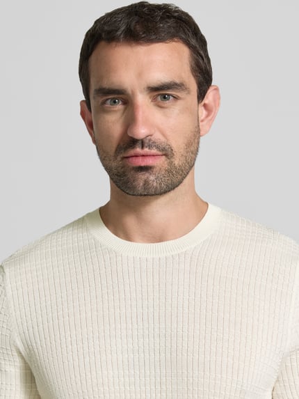 Männermodel trägt Strickshirt mit Strukturmuster Modell 'Elio' von JOOP!, cremefarben, reine Baumwolle, Nahaufnahme Oberkörper.