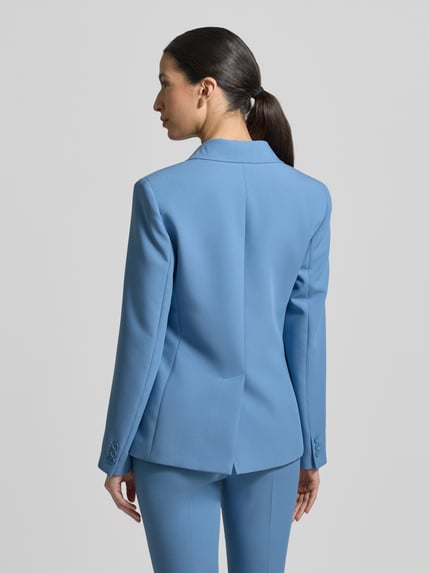 Vrouwenmodel draagt Slim Fit Blazer mit Viskose-Anteil van Weekend Max Mara in effen lichtblauw, reverskraag, borstzak, klepzakken, langem mouw, knoopsluiting, rugsplit; volledig beeld achteraan.