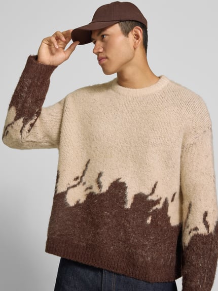 Männermodel trägt Strickpullover mit gerippten Abschlüssen von ANOTHER COTTON LAB, Beige-Braun, lockerer Schnitt, Nahaufnahme Oberkörper. Elastischer Material-Mix mit Lanawoll-Anteil, Rundhalsausschnitt, überschnittene Ärmel, Rückenlänge 62 cm, Ärmellänge 67 cm.