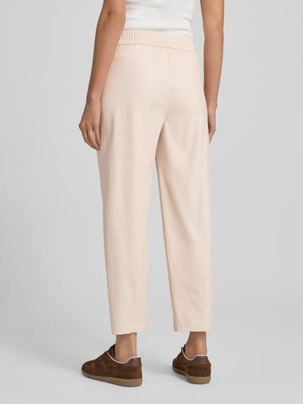 Frauenmodel trägt Jogpants aus Viskose-Mix mit elastischem Bund von Marc Cain in Beige, Regular-Fit, mit Tunnelzug und Eingrifftaschen, Rückansicht.