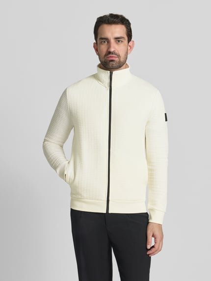 Männermodel trägt Loose Fit Sweatjacke aus Baumwoll-Mix von Tom Tailor Denim in effen crème met rits en label patch, geribde boorden, zijkantzakken, sweat crinkle structuur, Ganzkörperansicht von vorne.
