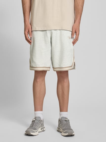 Männermodel trägt Shorts mit Strukturmuster und Label-Stitching von PEGADOR, Reine Baumwolle, Regular-Fit, Eingrifftaschen, Ganzkörperansicht von vorne.