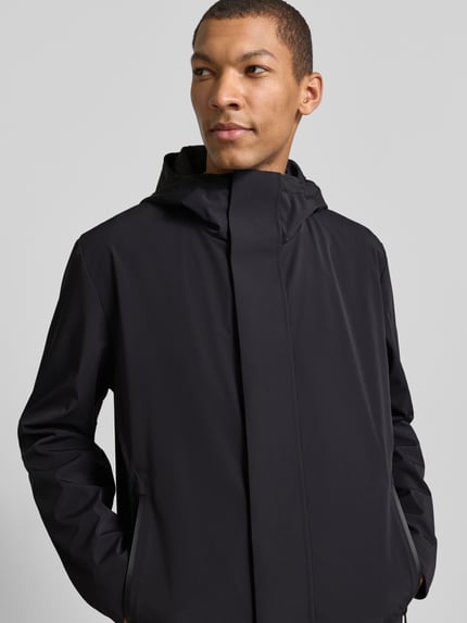 Mężczyzna nosi Regular Fit Funktionsmantel aus wasserabweisendem Material od Strellson, czarny, z kapturem i kieszeniami, materiał gładki, kurtka wodoodporna, wiatrówka, widok na górną część ciała z przodu