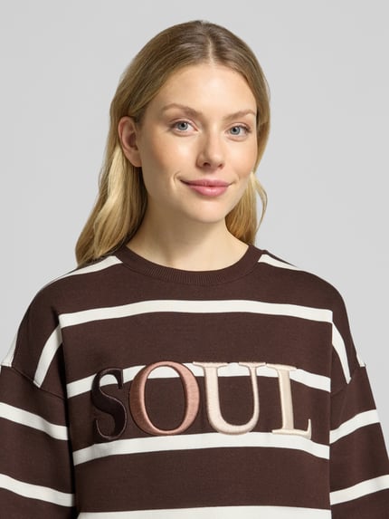 Frauenmodel trägt Oversized Sweatshirt aus mieszanka bawełny z wyhaftowanym napisem, prążkowane wykończenia i okrągły dekolt od Smith and Soul, brązowe i białe szerokie pasy, Ganzkörperansicht von vorne
