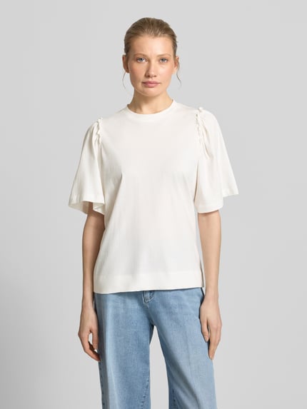 Frauenmodel trägt Regular Fit T-Shirt aus reiner Baumwolle Modell 'PENELOPE' von Selected Femme, Optik: Unifarben mit Rüschen-Applikation, Rundhals-Ausschnitt und 1/2-Arm, Ganzkörperansicht von vorne.