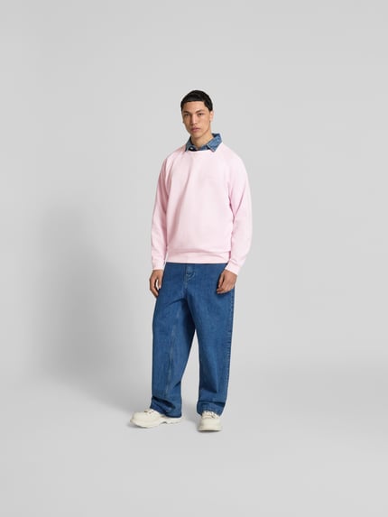 Männermodel trägt Relaxed Fit Sweatshirt aus Baumwolle von Closed in Rosa mit Raglanärmel, Rundhalsausschnitt, elastische Abschlüsse, Ganzkörperansicht von vorne. Rückenlänge bei Größe M 71 cm.